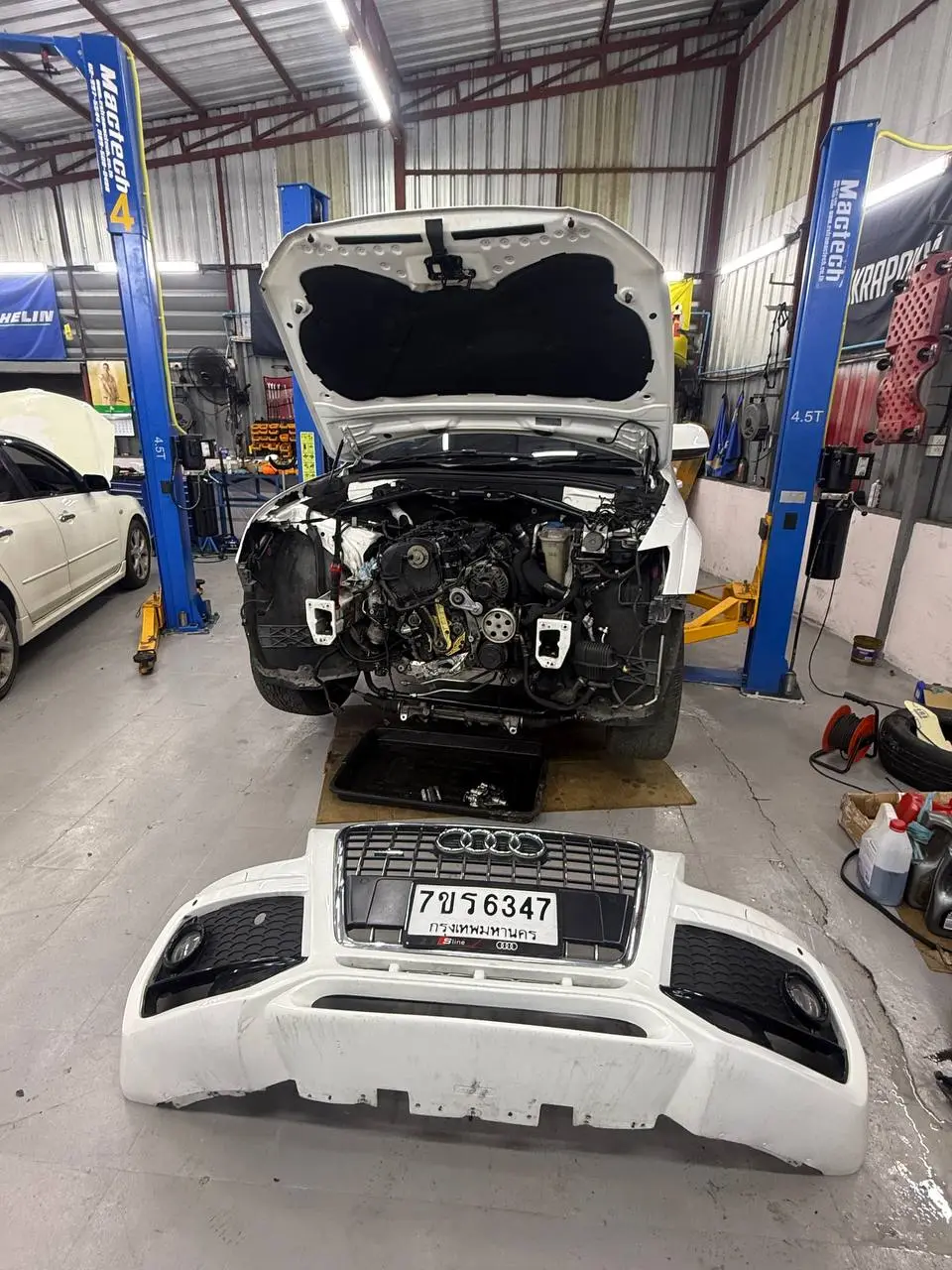 Audi Q5 2014: На фото автомобиль Audi Q5 2014, поднятый на подъёмнике. Откручен и снят передний бампер, виден двигатель и передняя часть кузова. Работа проводится в автосервисе.
